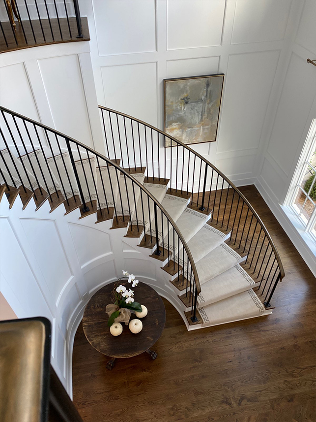Custom runner on a curved staircase in a double-height entrance hall